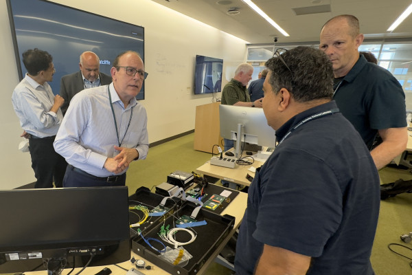 People in a conference room talking over computer hardware.